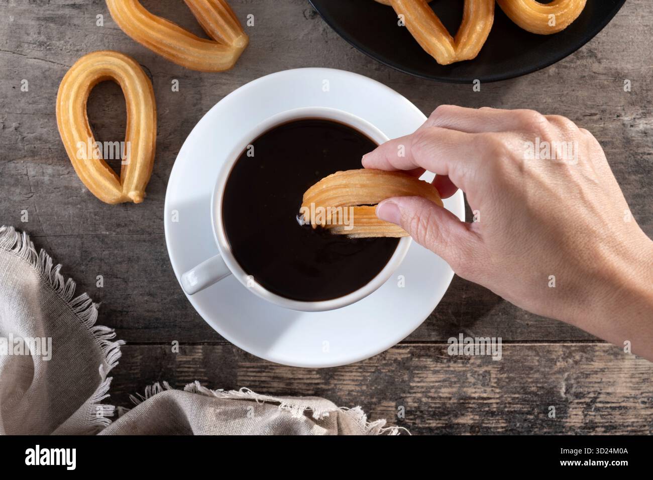 Mangiando tradizionali churros spagnoli con cioccolata calda su un tavolo di legno Foto Stock