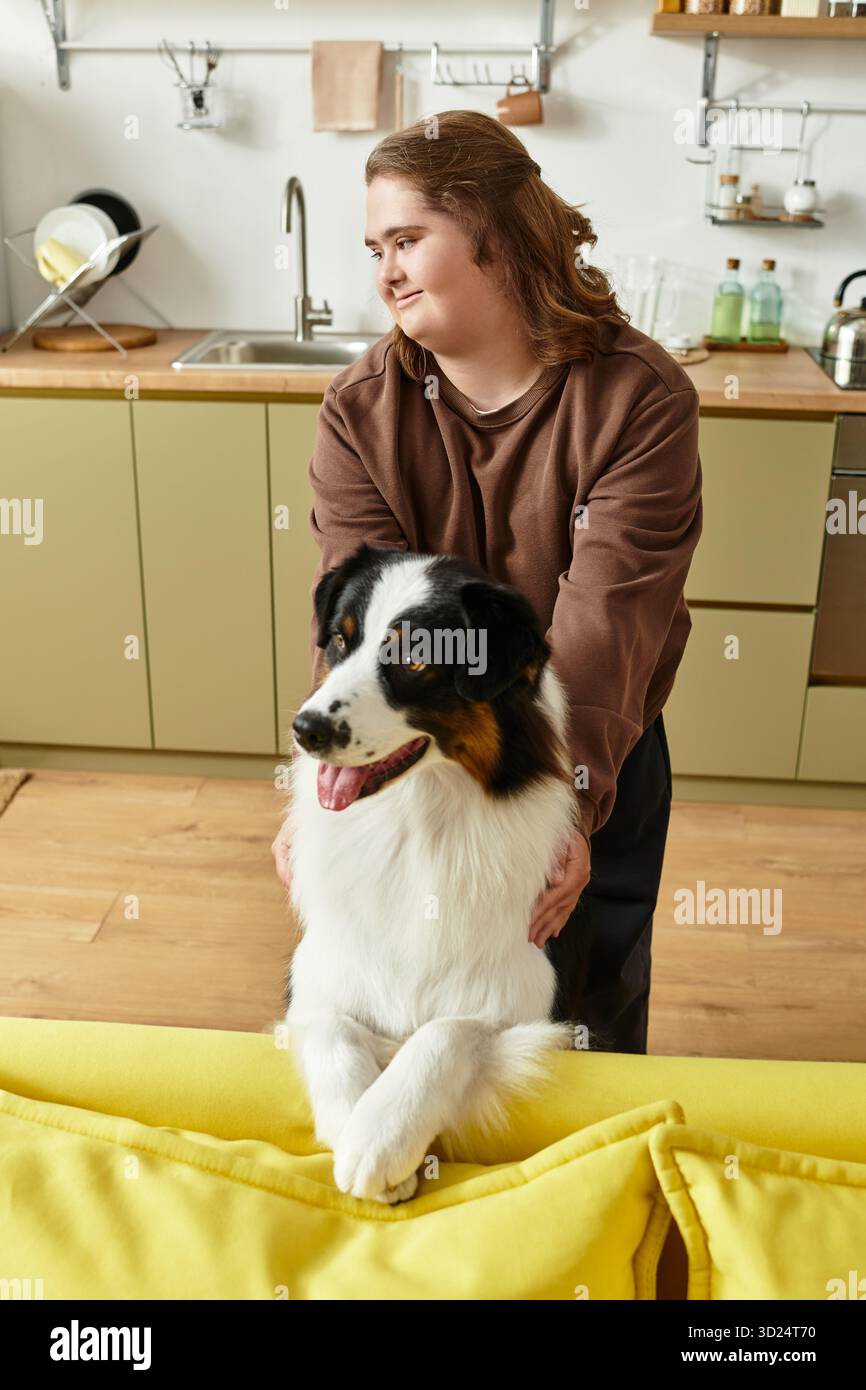 Una giovane donna con la sindrome di Down gode di compagnia con il suo cane in una casa accogliente. Foto Stock