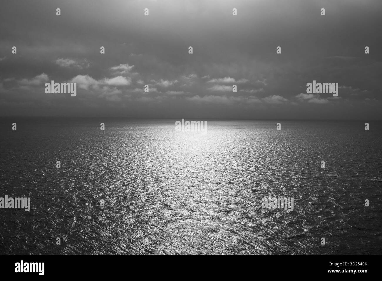 Vista in bianco e nero della luce del sole che si riflette su un mare calmo e vuoto Foto Stock