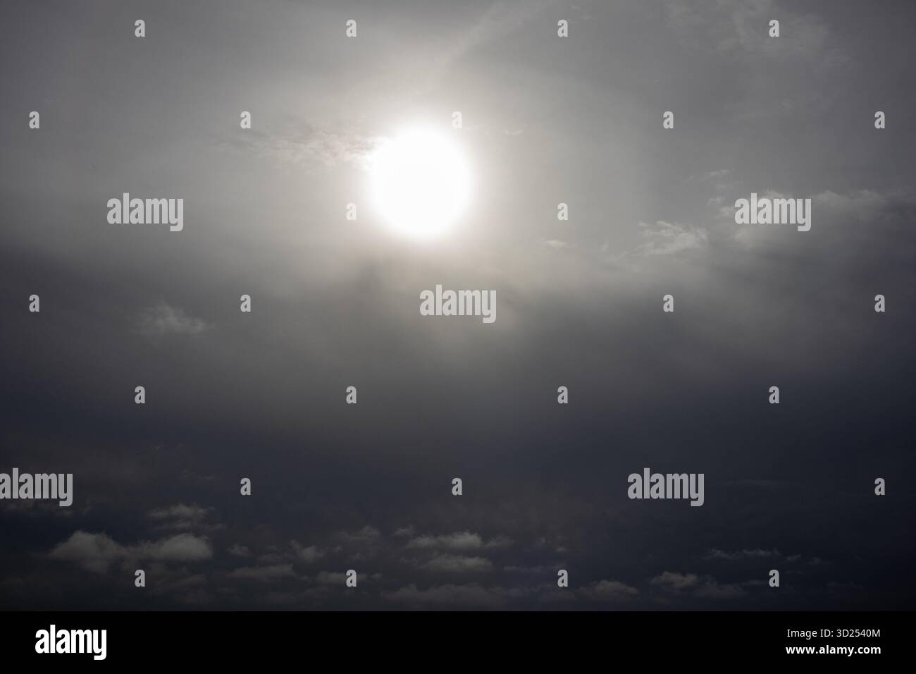 Vista di un grande sole nebulizzato che brilla leggermente attraverso gli strati di nuvole ricoperte Foto Stock
