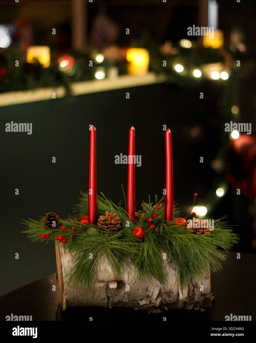 Tronco di Yule fatto in casa con candele rosse e rami di pino con luci di Natale Foto Stock