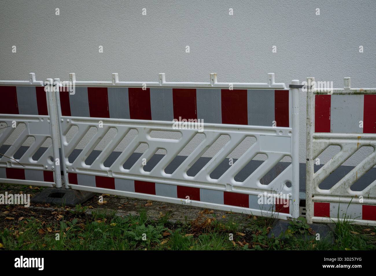 Barriera stradale temporanea bianca e rossa davanti a un muro dell'edificio per la costruzione di strade e la sicurezza dei pedoni. Foto Stock