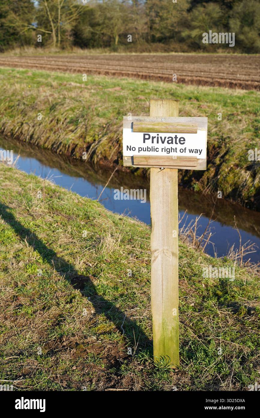 Privato nessun cartello pubblico di diritto di passaggio su un palo di legno ai margini di un campo e di un ruscello. Foto Stock