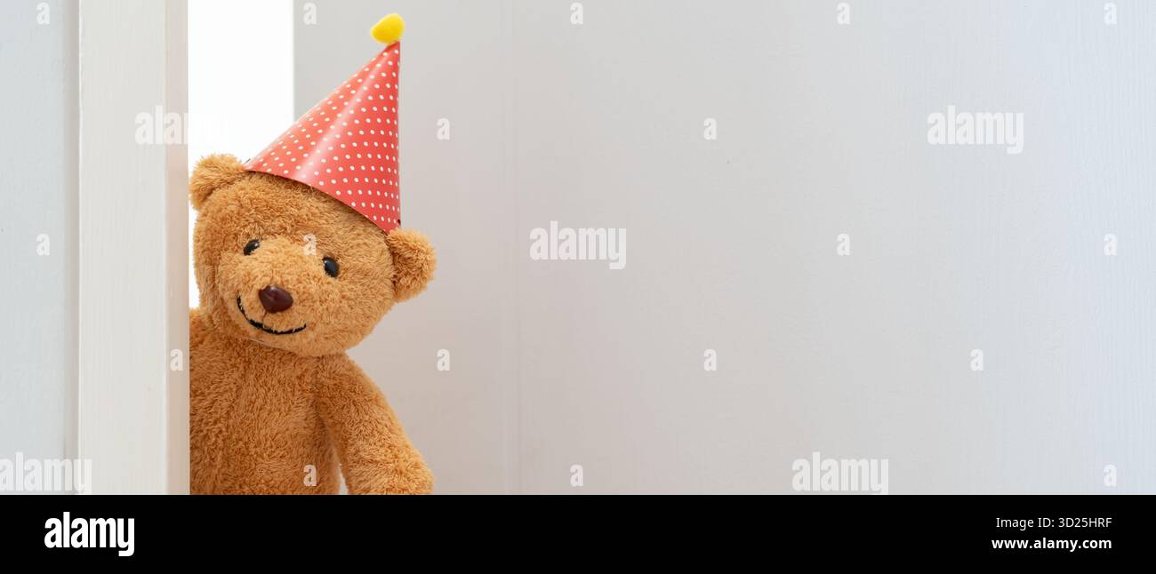 Il simpatico giocattolo marrone dell'orsacchiotto si intrufolerà dietro la porta e sorprenderà per congratularsi con i festeggiamenti speciali. bambino di gioco, asilo, benvenuto, giornata dei bambini Foto Stock