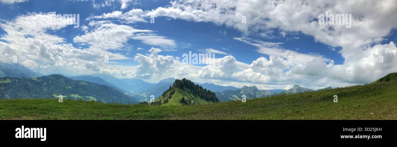 Un'ampia scena panoramica caratterizzata da verdi colline e un cielo blu luminoso adornato da nuvole di cumulus. Cattura l'incredibile bellezza della natura e del respiro Foto Stock