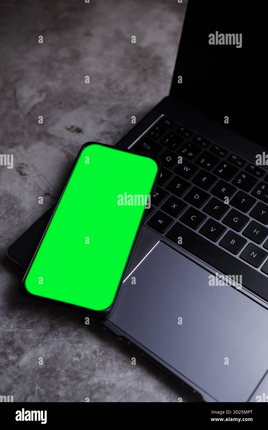 Mockup dello schermo del telefono posizionato sul desktop del notebook. Foto Stock