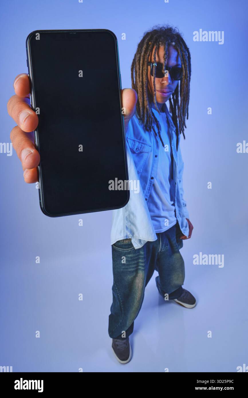 Persona con dreadlock che presenta uno smartphone con uno schermo vuoto Foto Stock