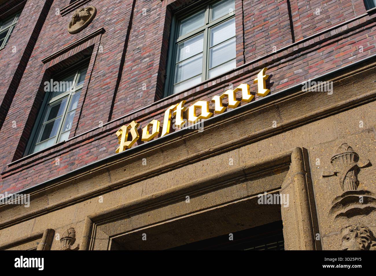 Insegna dorata "Postamt" su uno storico edificio in mattoni sotto la luce del giorno nel quartiere Oberkassel di Düsseldorf Foto Stock