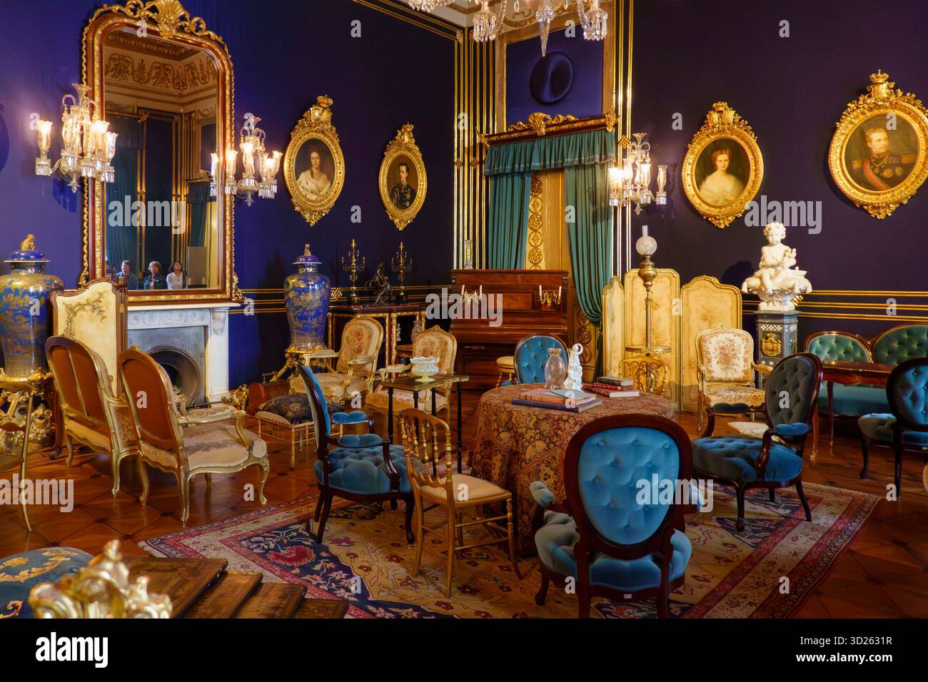 Camera riccamente decorata con mobili antichi, ritratti ornati, lampadari e pareti blu intenso al Palazzo di Ajuda, Lisbona, Portogallo, Europa Foto Stock