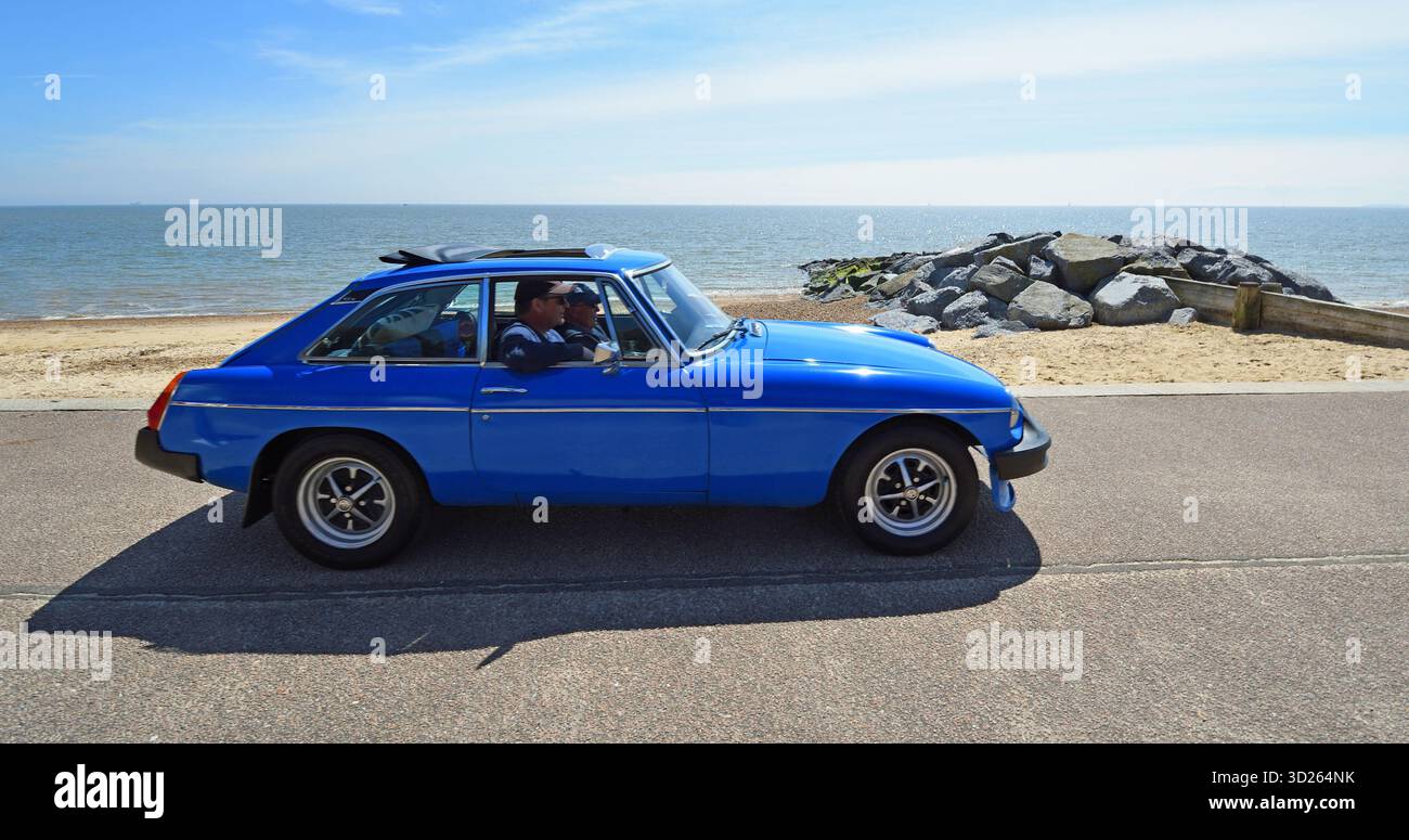 Classic Blue MG MGB GT sulla spiaggia lungomare e sul mare sullo sfondo Foto Stock