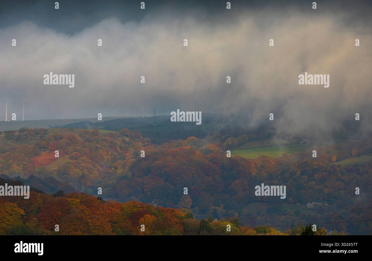 I colori autunnali sulla collina Pennine sopra Todmorden, West Yorkshire, come la nebbia di prima mattina avvolge i lontani mulini a vento e le turbine dando alle colline e alle brughiere un aspetto quasi dipinto. Foto Stock
