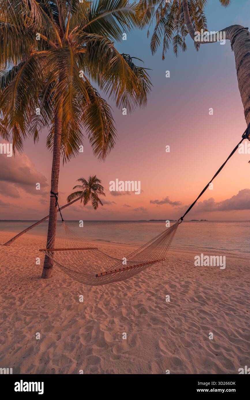 Tranquillo e colorato tramonto magico con palme e amaca altalena, rilassante vista sull'oceano, perfetto paesaggio estivo sulla spiaggia Foto Stock