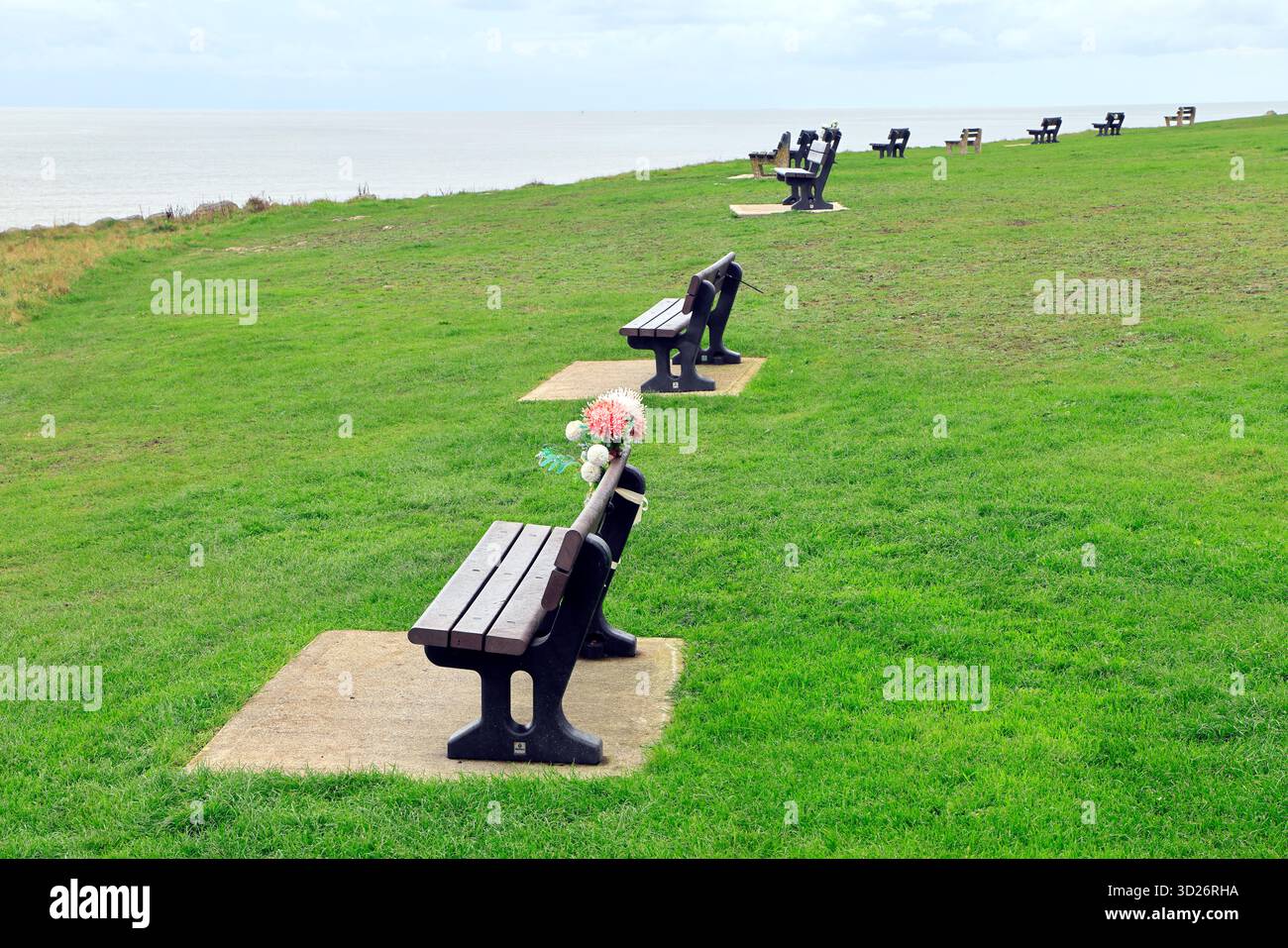 Molte panchine pubbliche di fila si affacciano sul mare di Porthcawl, Galles del Sud, Regno Unito. Presa ottobre 2025. Autunno Foto Stock