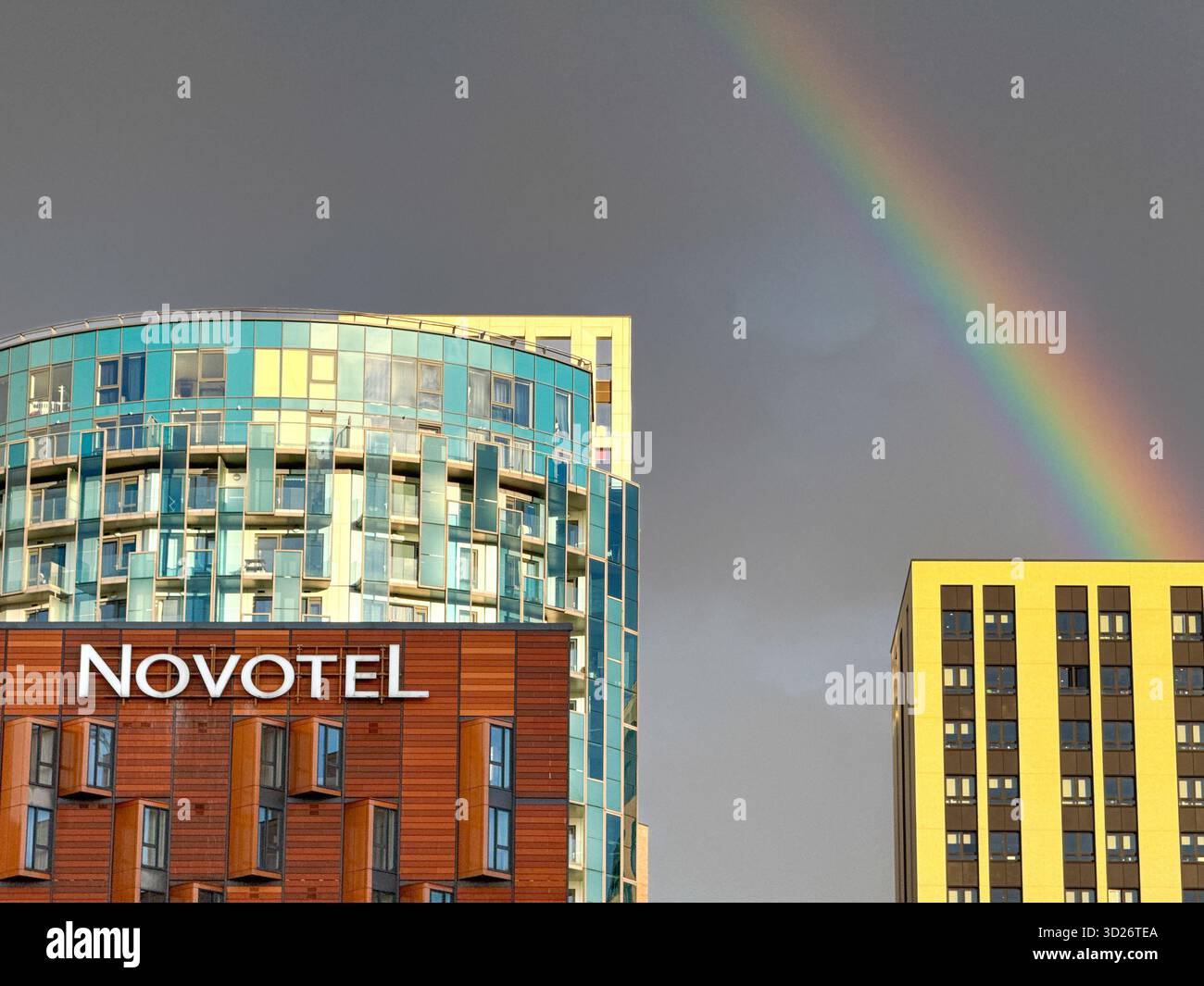 Londra, Inghilterra, Regno Unito - 25 ottobre 2025: Vista frontale esterna dell'hotel Novotel fuori dallo stadio di Wembley con un arcobaleno sullo sfondo. - Immagine stock catturata con smartphone