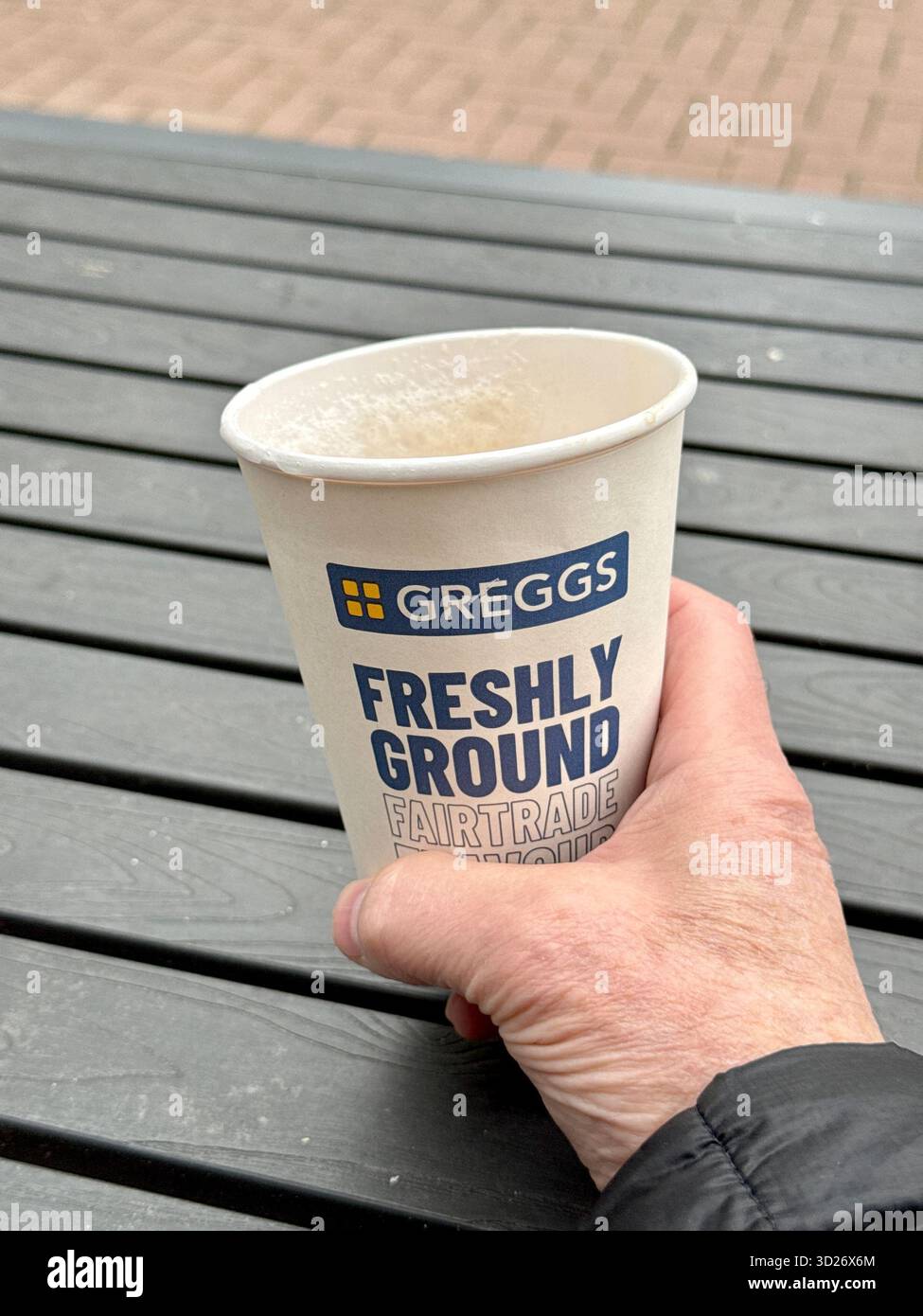 Cardiff, Galles, Regno Unito - 17 ottobre 2025: Mano di una persona che tiene una tazza di caffè Greggs in una tazza usa e getta - Immagine stock catturata con smartphone