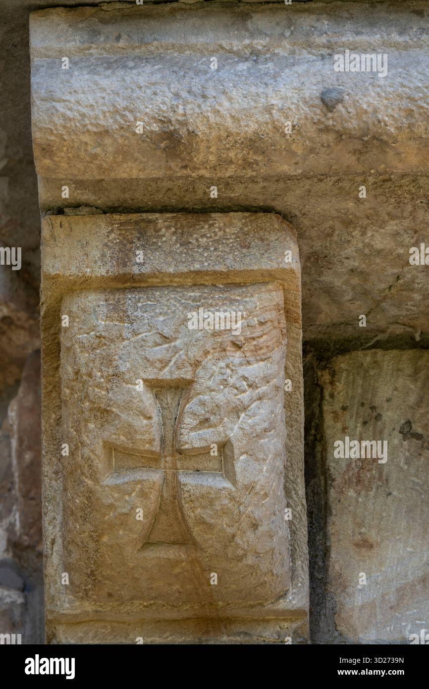 Croce templare, intaglio romanico, sulla Chiesa di San Cipriano de Bolmir, tempio romanico del XII secolo, villaggio di Bolmir, Campoo de Enmedio, Cantabria, Spagna. Foto Stock