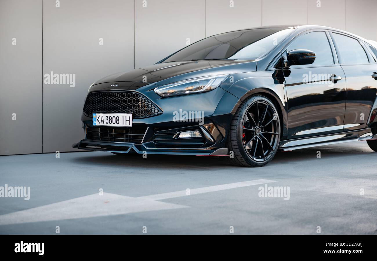 Angolo anteriore sinistro della Ford Focus nera. Primo piano di una berlina modificata scura con kit widebody. Foto Stock