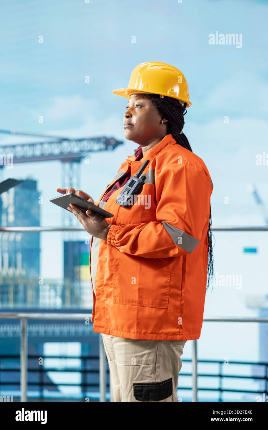 Esperto di piattaforme offshore che indossa un casco protettivo che controlla le operazioni del ponte, garantendo la conformità ai protocolli di sicurezza. Donna che lavora per un'azienda del gas che esegue la manutenzione preventiva dei carri di perforazione Foto Stock