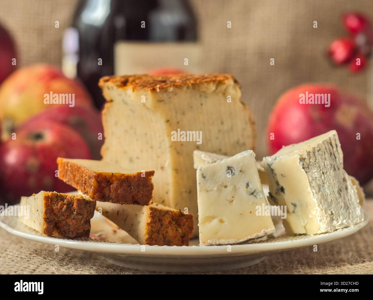 La selezione di formaggi gourmet include il blu dana, gorgonzola e pepe Jack con vino e mele in un ambiente rustico Foto Stock