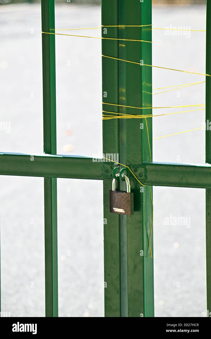 Un cancello verde con un lucchetto. Il lucchetto è giallo e presenta un'etichetta Foto Stock