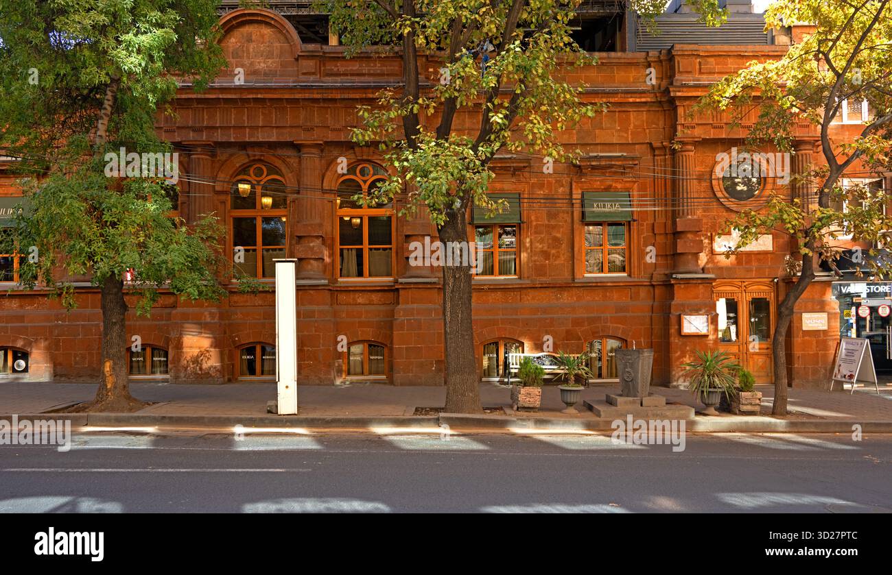 Erevan, Armenia 10.16.2025. Un edificio in mattoni con un cartello bianco sul marciapiede. L'edificio ha molte finestre e un balcone Foto Stock