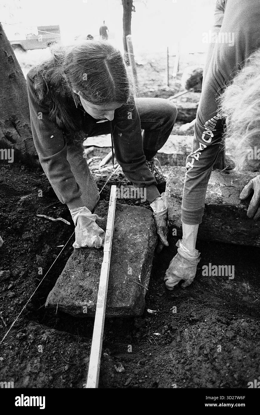 Questa fotografia in bianco e nero raffigura i volontari che partecipano al primo viaggio di servizio internazionale del Sierra Club nel Peak District, in Inghilterra. Due individui lavorano insieme per misurare una struttura in pietra, insieme agli ambientalisti locali. L'immagine cattura un momento di collaborazione durante un progetto di servizio ambientale. Foto Stock