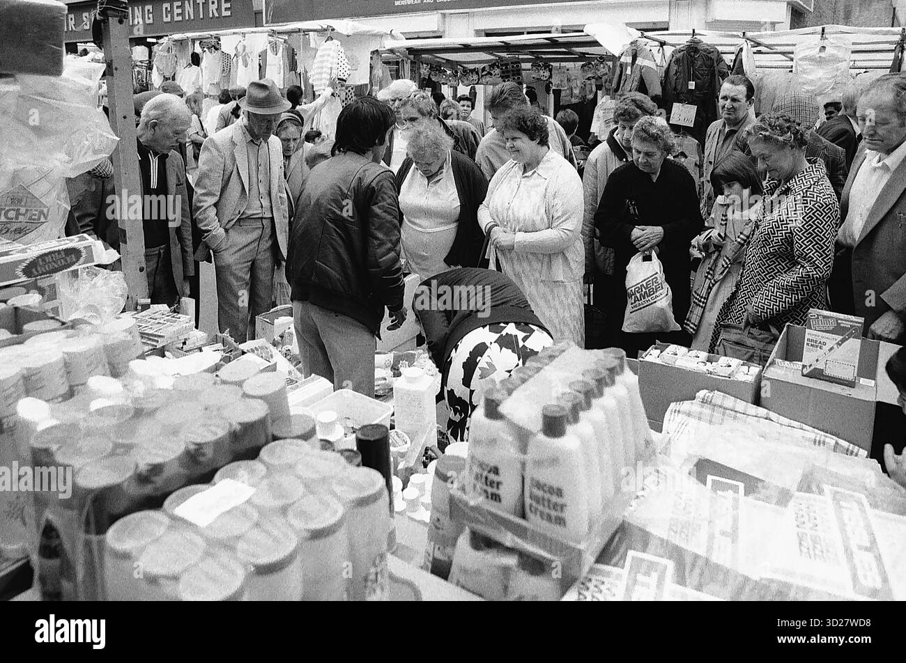 Una scena movimentata al Camden Lock Market, Londra. Gli amanti dello shopping navigano tra le corsie affollate, piene di una vasta selezione di merci, creando un'istantanea vibrante di questa iconica destinazione londinese. L'atmosfera vivace del mercato è palpabile, mostrando il suo fascino duraturo come fulcro del commercio e della cultura. Foto Stock
