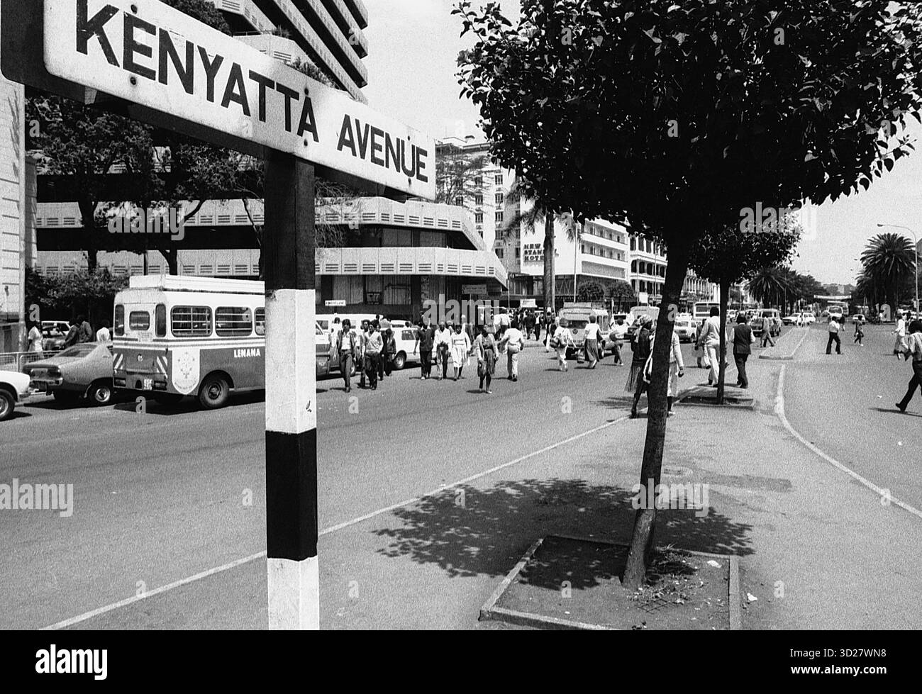 La vivace Kenyattta Avenue di Nairobi si anima in questa classica immagine in bianco e nero. L'iconica avenue, una strada principale nel cuore della città, è punteggiata di pedoni e veicoli. L'architettura degli edifici circostanti, un mix di strutture moderne e più vecchie, suggerisce la ricca storia di Nairobi e il suo continuo sviluppo. Questa istantanea cattura un momento di attività quotidiana, offrendo uno sguardo nel vivace cuore della capitale del Kenya. Foto Stock