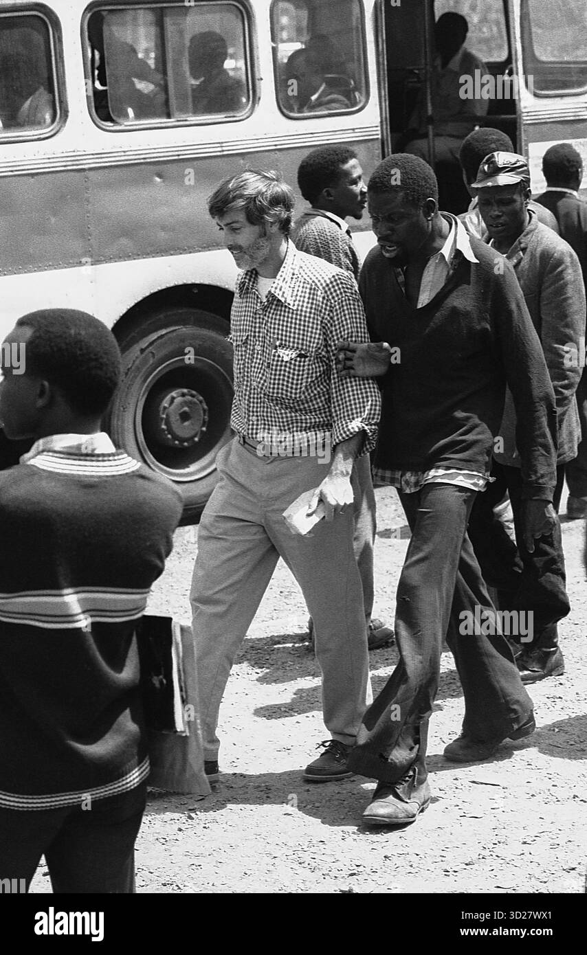 Nairobi, Kenya – Un momento sincero cattura la vivace energia di questa città dell'Africa orientale. Un turista occidentale interagisce con i residenti locali, mentre un autobus bianco della città si trova nelle vicinanze, una vista comune nel vivace paesaggio urbano di Nairobi. L'immagine evoca un senso di vita quotidiana e di scambio culturale nel cuore del Kenya. Foto Stock