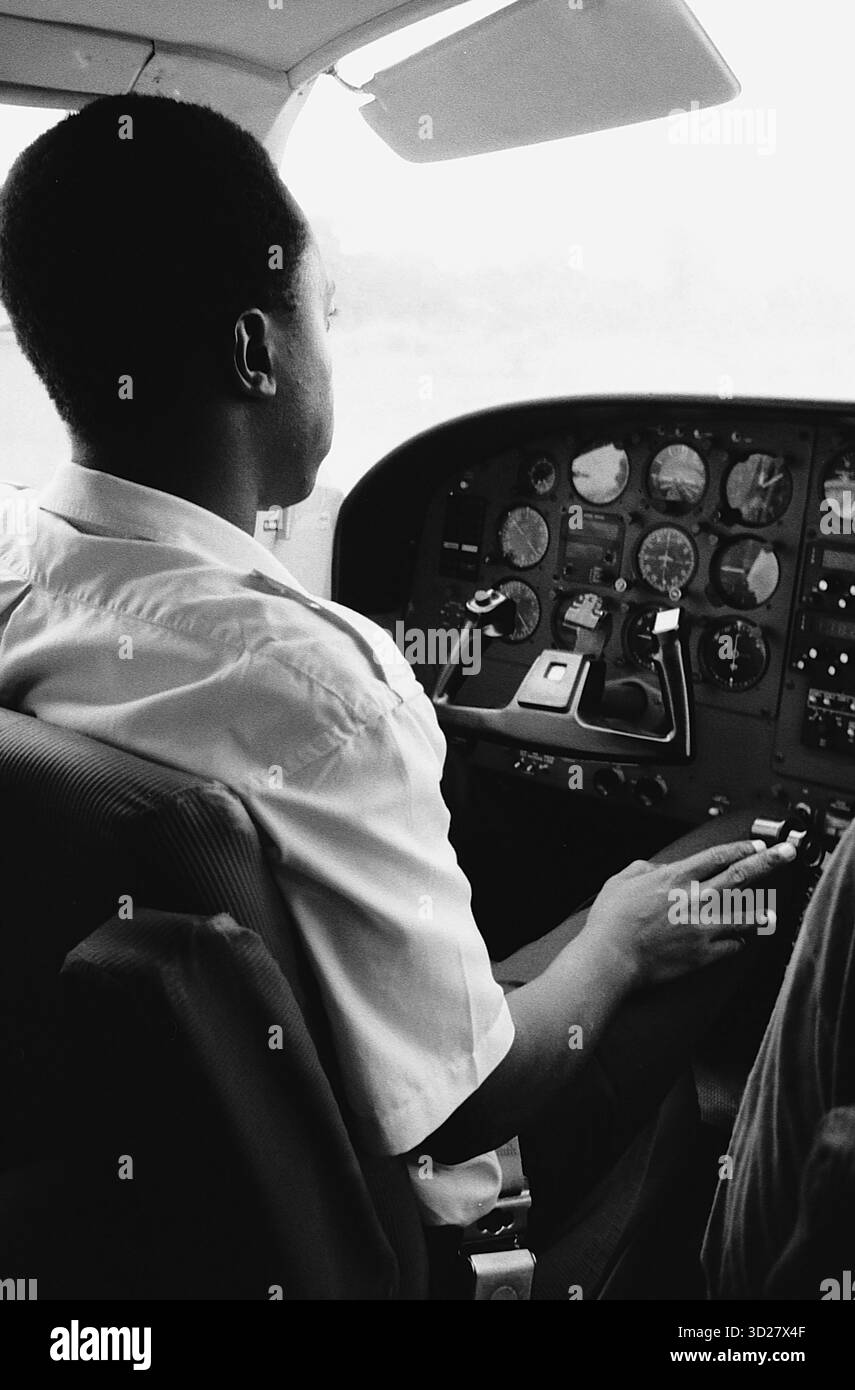 Sopra il Serengeti: Un pilota vedrà i vasti paesaggi della Tanzania. Questa sorprendente fotografia in bianco e nero cattura la prospettiva di un pilota che sorvola la vasta distesa della Tanzania. Il complesso quadro strumenti dell'aereo domina il telaio, suggerendo le sfide e i premi della navigazione in questa iconica nazione africana. L'immagine evoca un senso di avventura e sottolinea la bellezza remota della Tanzania, offrendo un punto di vista unico sul terreno diversificato del paese. Foto Stock