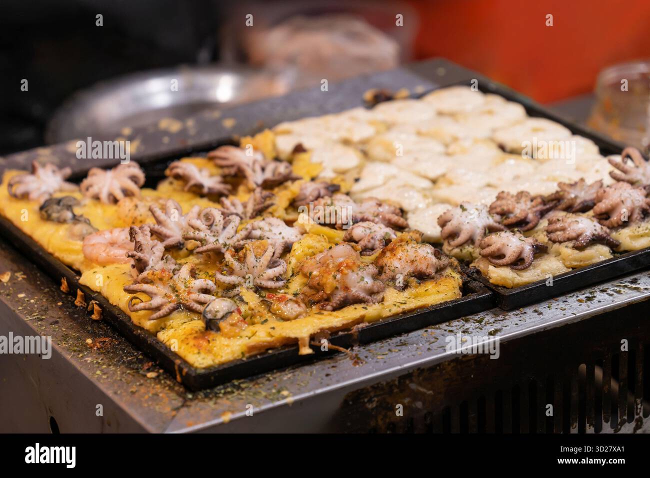 Grigliate con polpette di polpo su una grande griglia al mercato notturno. Foto Stock