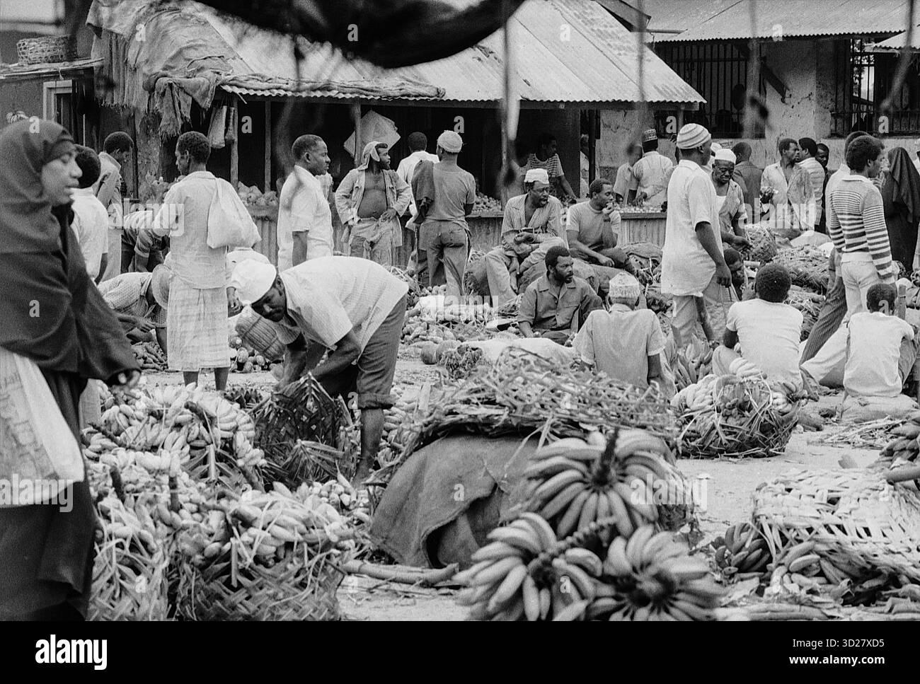 Zanzibar Market Scene: Un vivace mercato a Zanzibar, Tanzania, che mostra il commercio quotidiano con venditori e acquirenti locali in mezzo a una vibrante gamma di merci. La scena cattura l'essenza del commercio tradizionale e dell'interazione con la comunità all'interno della città storica. Foto Stock