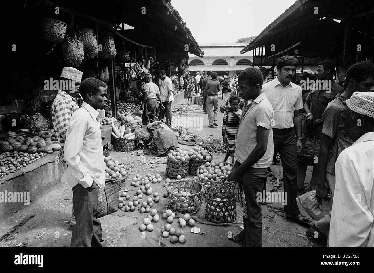 Zanzibar Market Buzz: Una vivace scena si svolge nel vivace mercato di Zanzibar, Tanzania. Gli acquirenti e i venditori navigano tra i passaggi affollati, circondati da una vasta gamma di merci. L'immagine in bianco e nero cattura l'energia e il commercio della vita quotidiana in questo storico centro commerciale dell'Africa orientale. Foto Stock