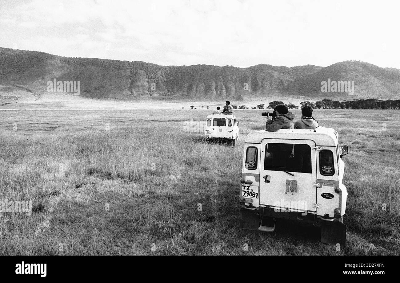 Safari Adventure in the Crater: I turisti attraversano le vaste praterie del Ngorongoro Crater National Park in Tanzania, circondati dal suggestivo paesaggio vulcanico. Foto Stock