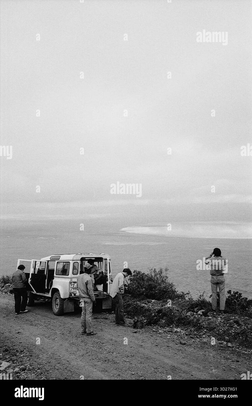 I turisti osservano la vasta distesa del cratere di Ngorongoro in Tanzania. L'iconica caldera, patrimonio dell'umanità dell'UNESCO, domina il paesaggio, offrendo viste mozzafiato delle sue formazioni geologiche uniche e della variegata fauna selvatica. Foto Stock