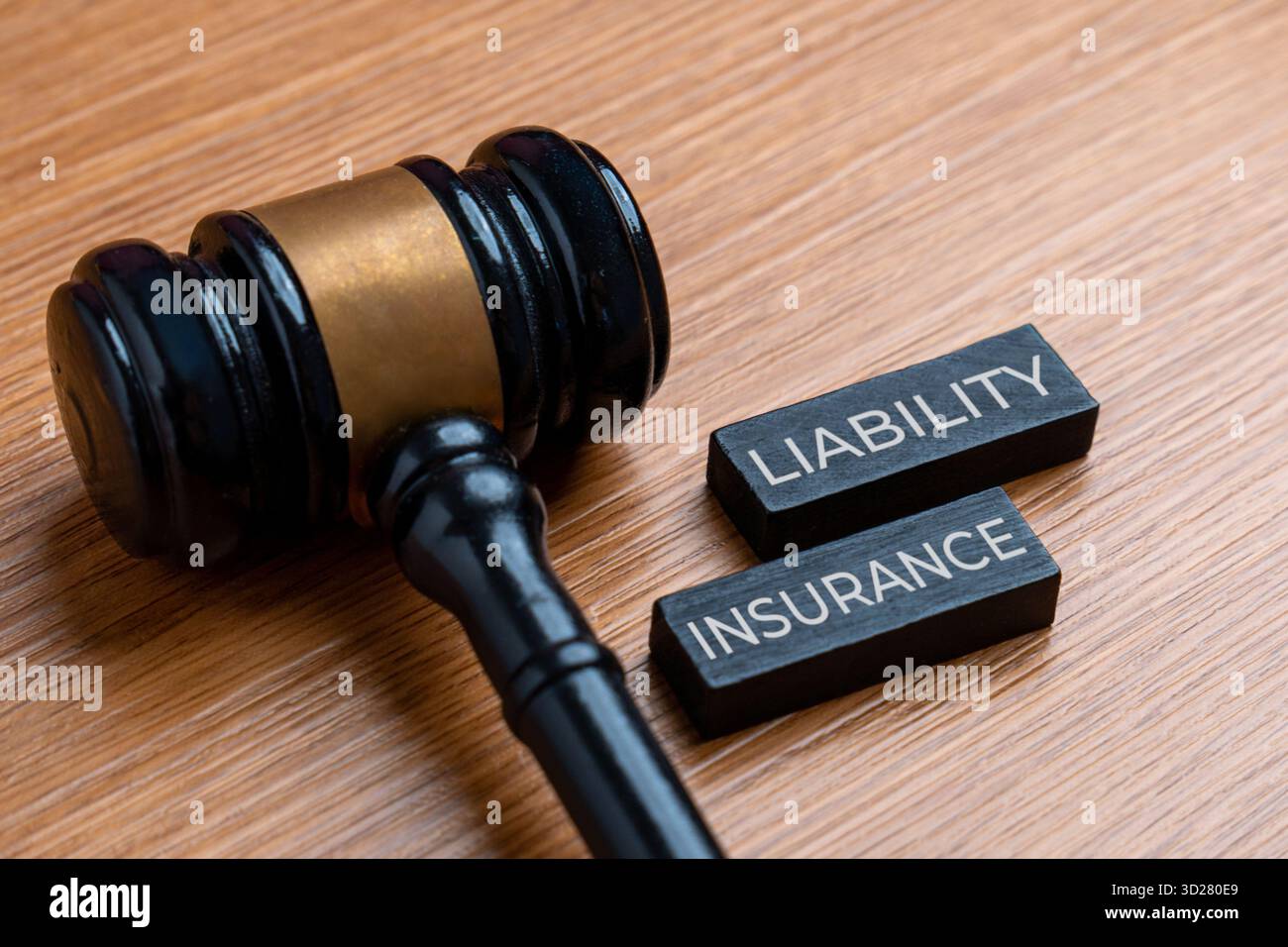 Un martelletto su una scrivania accanto a due blocchi di legno impilati con la scritta ASSICURAZIONE di responsabilità. Concetto di legge. Foto Stock