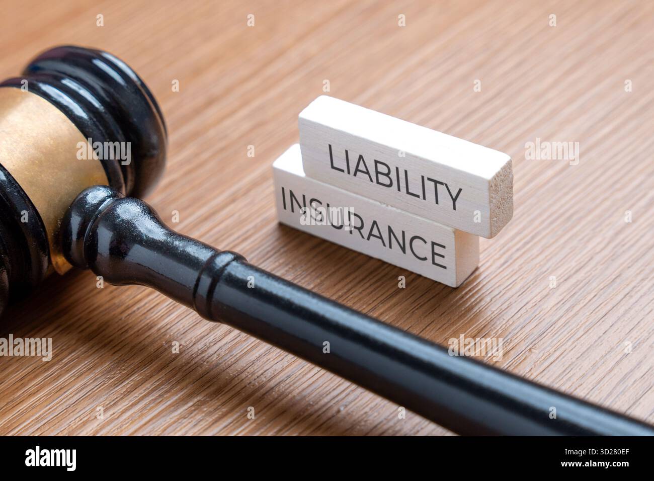 Un martelletto su una scrivania accanto a due blocchi di legno impilati con la scritta ASSICURAZIONE di responsabilità. Concetto di legge. Foto Stock