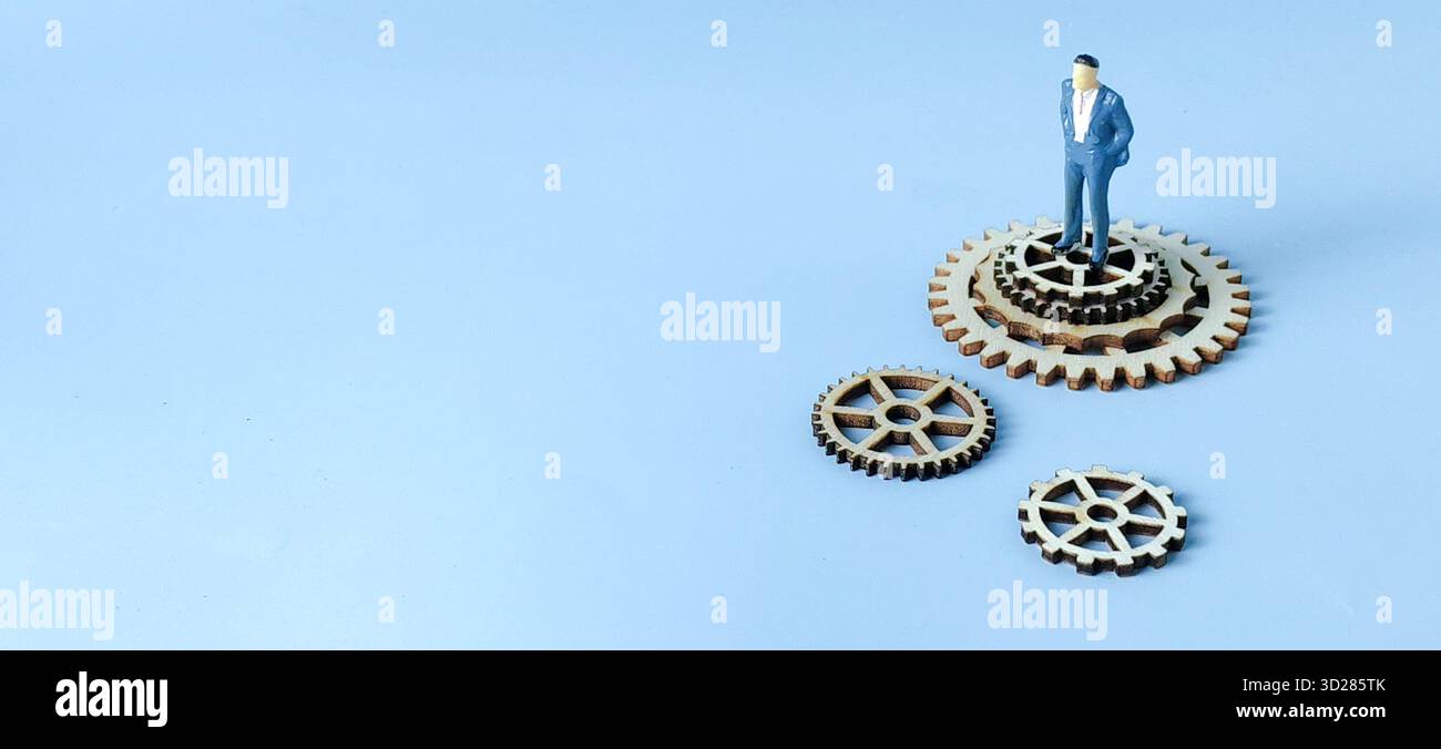 Corporate Hierarchy and Business System Strategy: Figura dell'uomo d'affari e ingranaggi in legno scollegati Foto Stock