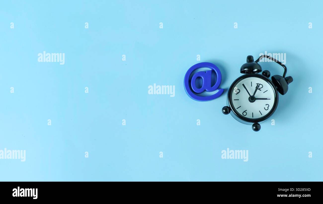 Blu a Symbol accanto alla sveglia che rappresenta il tempo di risposta e-mail, l'urgenza digitale e le scadenze di comunicazione Foto Stock