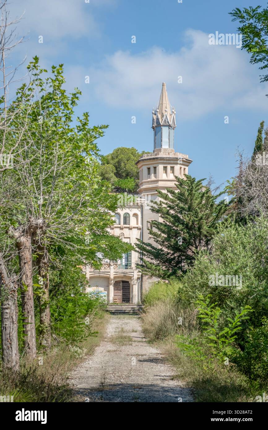Vista frontale del modernista Masia Cal Pla, un bene culturale di interesse locale, con la sua torre centrale, visto attraverso il sentiero sopraelevato di Cunit, Spagna Foto Stock