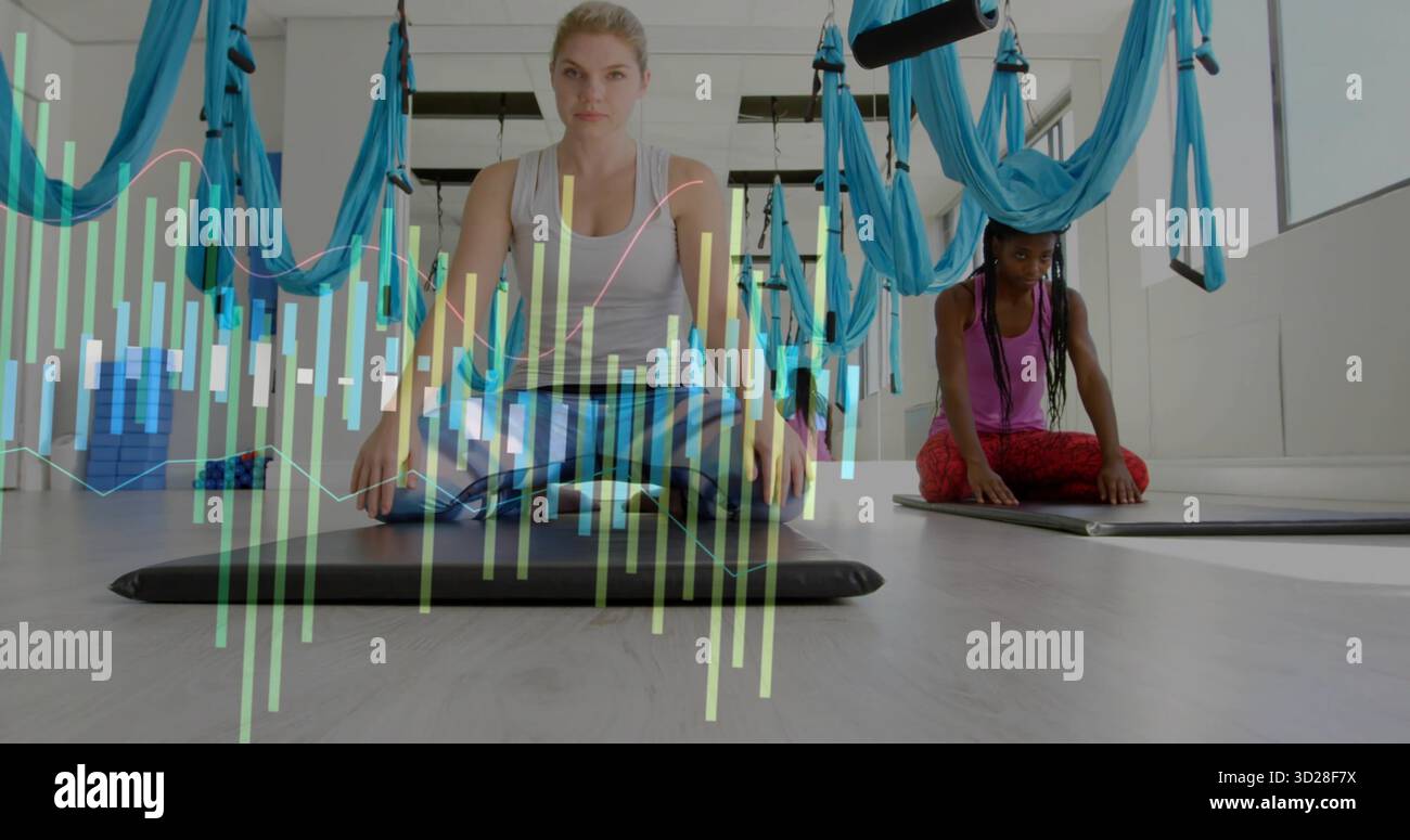 Donna inginocchiata che indossa abbigliamento sportivo analizzando i dati biometrici sul tappetino in studio con amache aeree Foto Stock