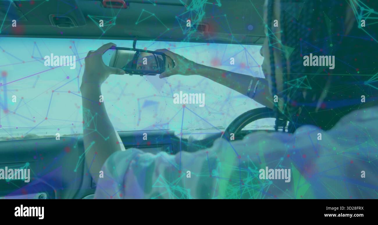 Donna che utilizza lo smartphone che controlla il riflesso in cabina, lo specchio dell'aletta parasole, il volante, lo spazio per copiare Foto Stock