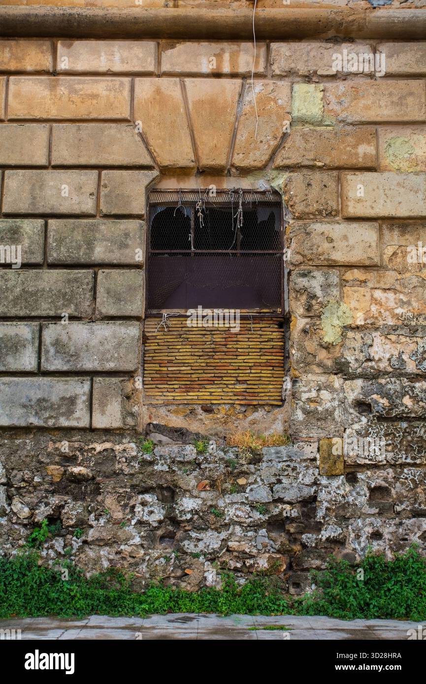 Una finestra in un muro di conci del XVII-XVIII secolo in foro Italico a Palermo, Sicilia, Italia. La parte inferiore del muro è invece costruita in muratura di macerie Foto Stock