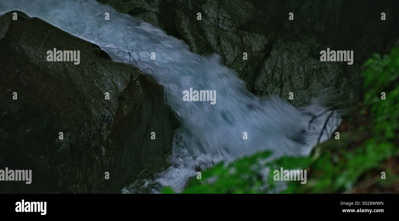Il fiume turbolento scorre rapidamente tra le rocce aspre e umide Foto Stock