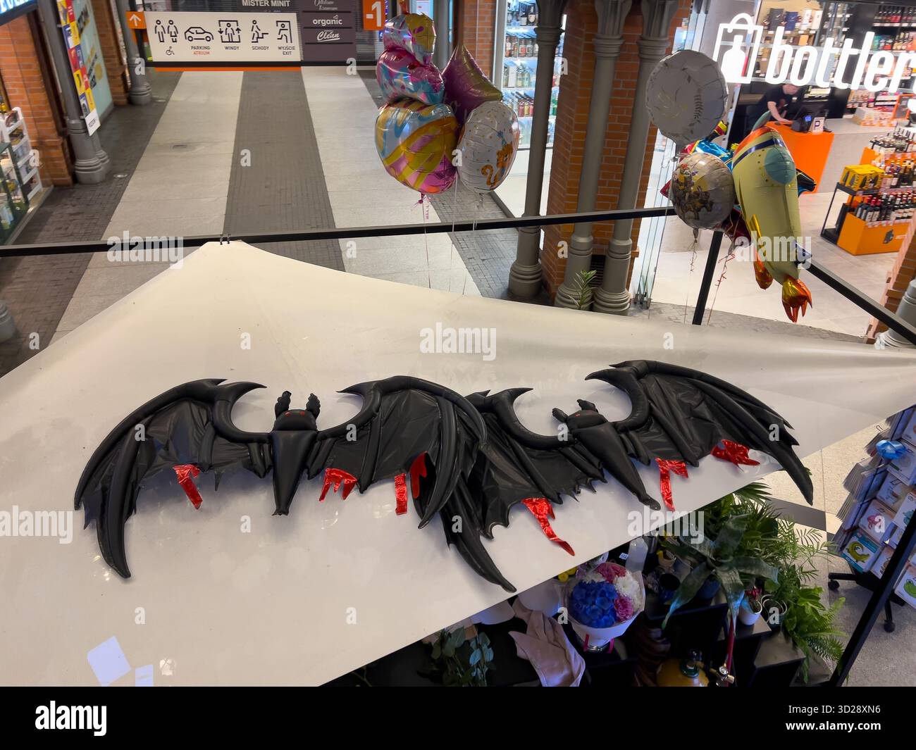Poznan, Polonia - 10 ottobre 2025: Prospettiva dall'alto di una decorazione di pipistrelli gonfiabili neri con accenti rossi, sospesa in un centro commerciale, creando fe Foto Stock