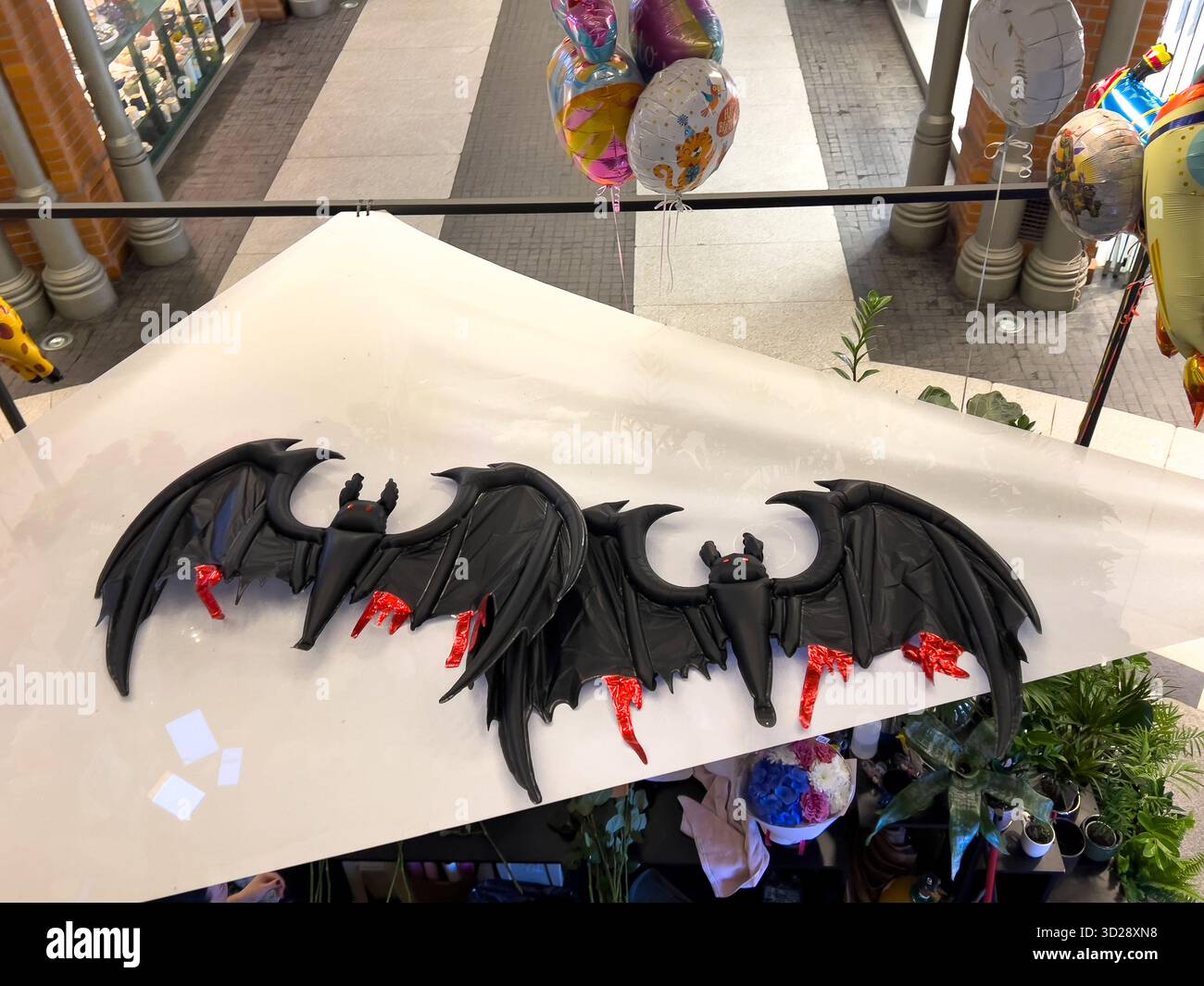 Poznan, Polonia - 10 ottobre 2025: Pipistrelli neri decorativi con accenti rossi adornano una barriera bianca in un atrio pubblico, ideale per Halloween o vigilia fantasy Foto Stock