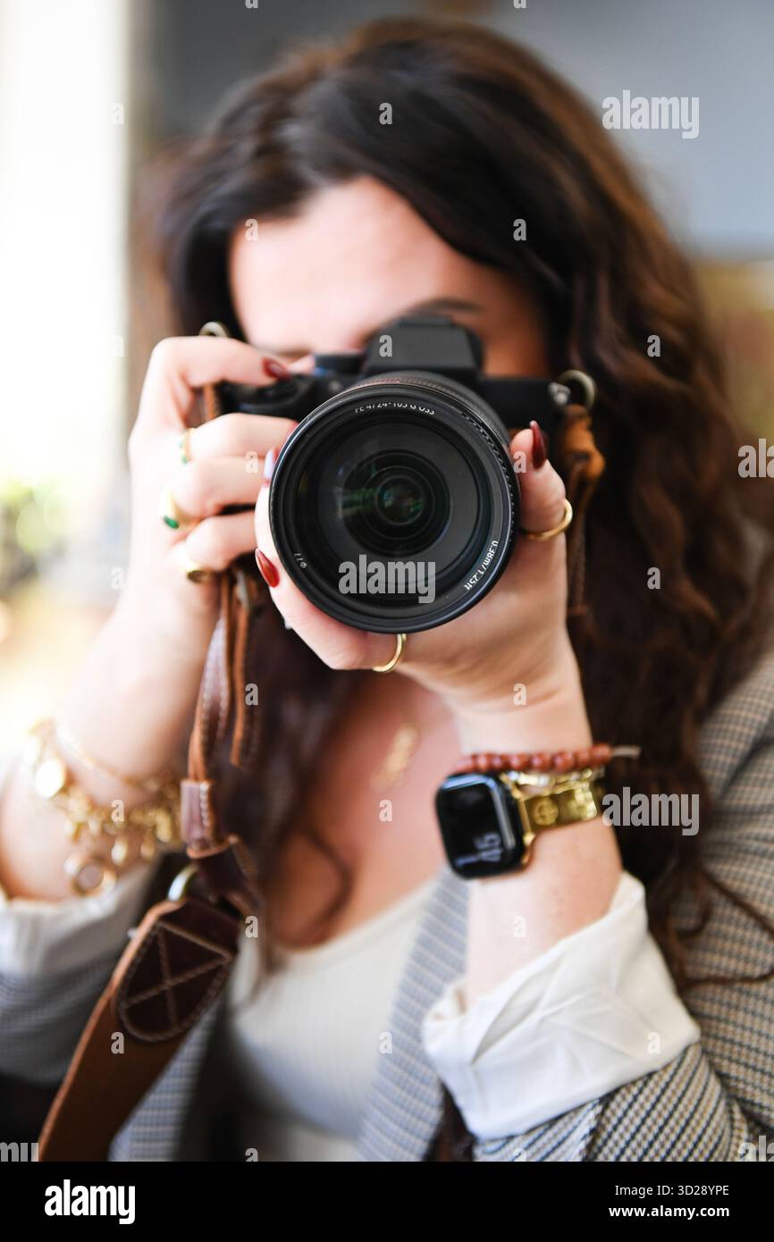 Donna che punta la fotocamera direttamente allo spettatore, primo piano con fa sfocato Foto Stock