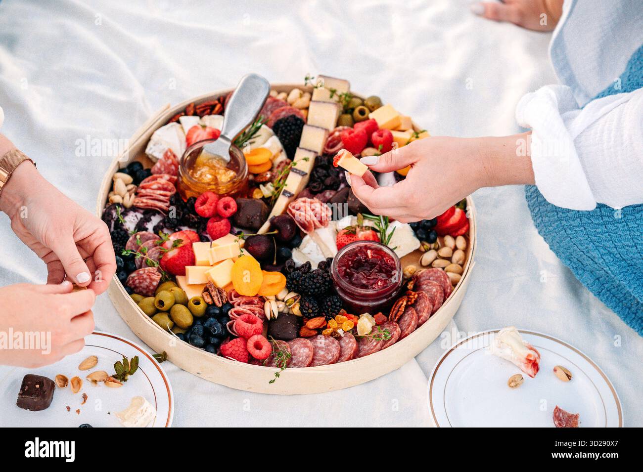 Gruppo che si gode un tagliere di salumi con affettati assortiti e formaggi Foto Stock