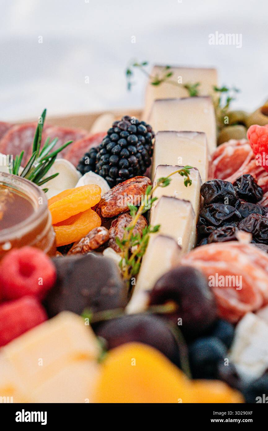 Primo piano di spicchi di formaggio, more e frutta secca a bordo. Foto Stock