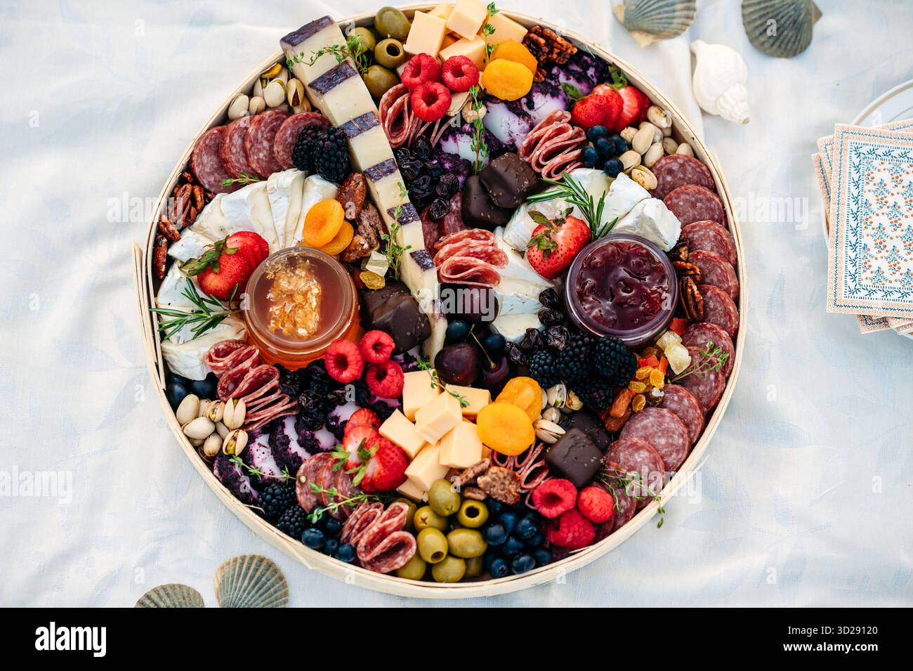 Tagliere rotondo di salumi con formaggio, frutta e carni su un panno Foto Stock